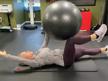Author Marisa Savino uses a fitness ball for stability during an exercise.