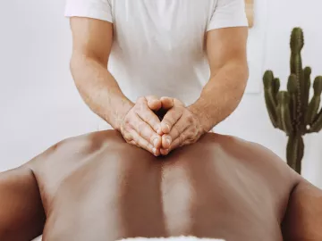 A massage therapist massages a client's back.