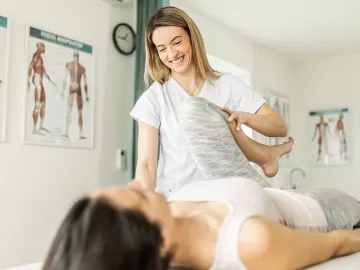 A female massage therapist stretches the leg of a client.
