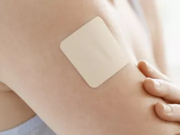 A nondescript, square medication patch is on a person's arm.