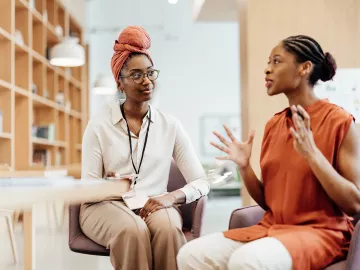 Two women are seated in conversation.