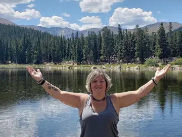 Heather Topoly standing with arms outstretched in the mountains.
