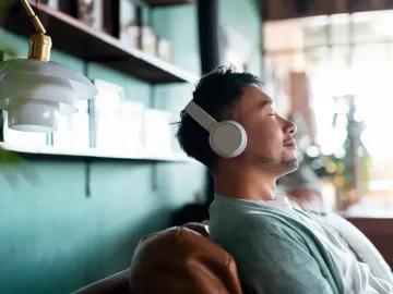A man sits back and relaxes with his headphones on.