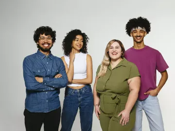 Four individuals of various ethnicities smile for a photo. 