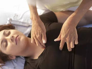 Woman lying on massage table receiving therapeutic touch.