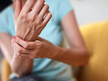 A female grasps her wrist.
