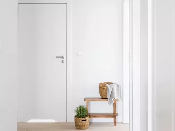 A hallway in an office leading to a small table with a towel and a door.