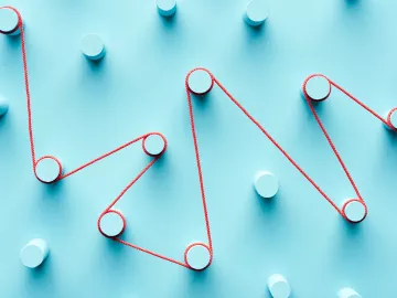 A red string winds around pegs on a blue board.