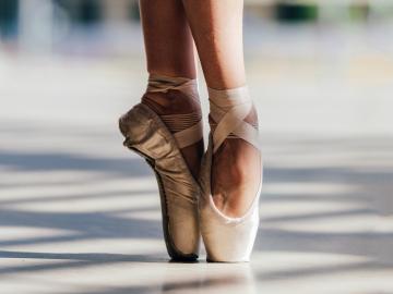 A pair of feet on tip toe in pointe shoes.