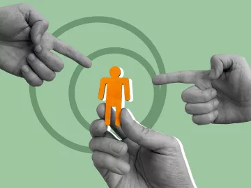 One hand holds up a cutout of a person, while two other hands point at the figure.
