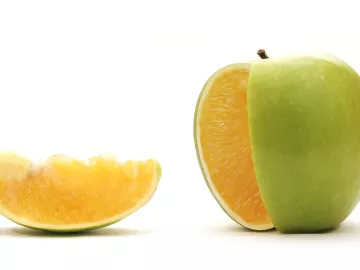 A piece of fruit that is green apple on the outside, but orange on the inside.