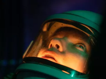 A person in a deep-sea diving suit stares into the depths.