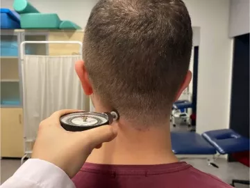 A client has a pain pressure threshold algometer held at their neck.
