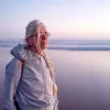 An elderly lady looks out across an ocean.