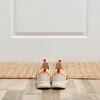 A pair of shoes sits in front of a door and welcome mat.