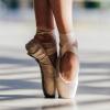 A pair of feet on tip toe in pointe shoes.