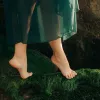 A dancer on their toes walks on a mossy bed.