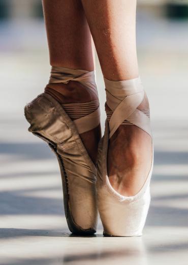 A pair of feet on tip toe in pointe shoes.