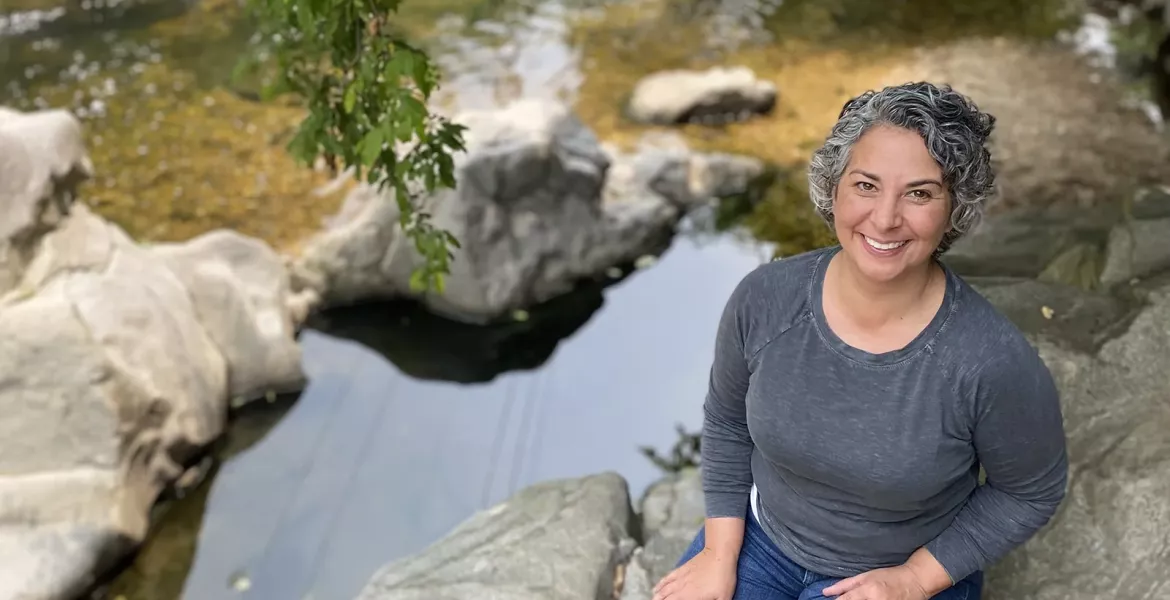 A professional portrait of Kerry Jordan sitting by a creek.